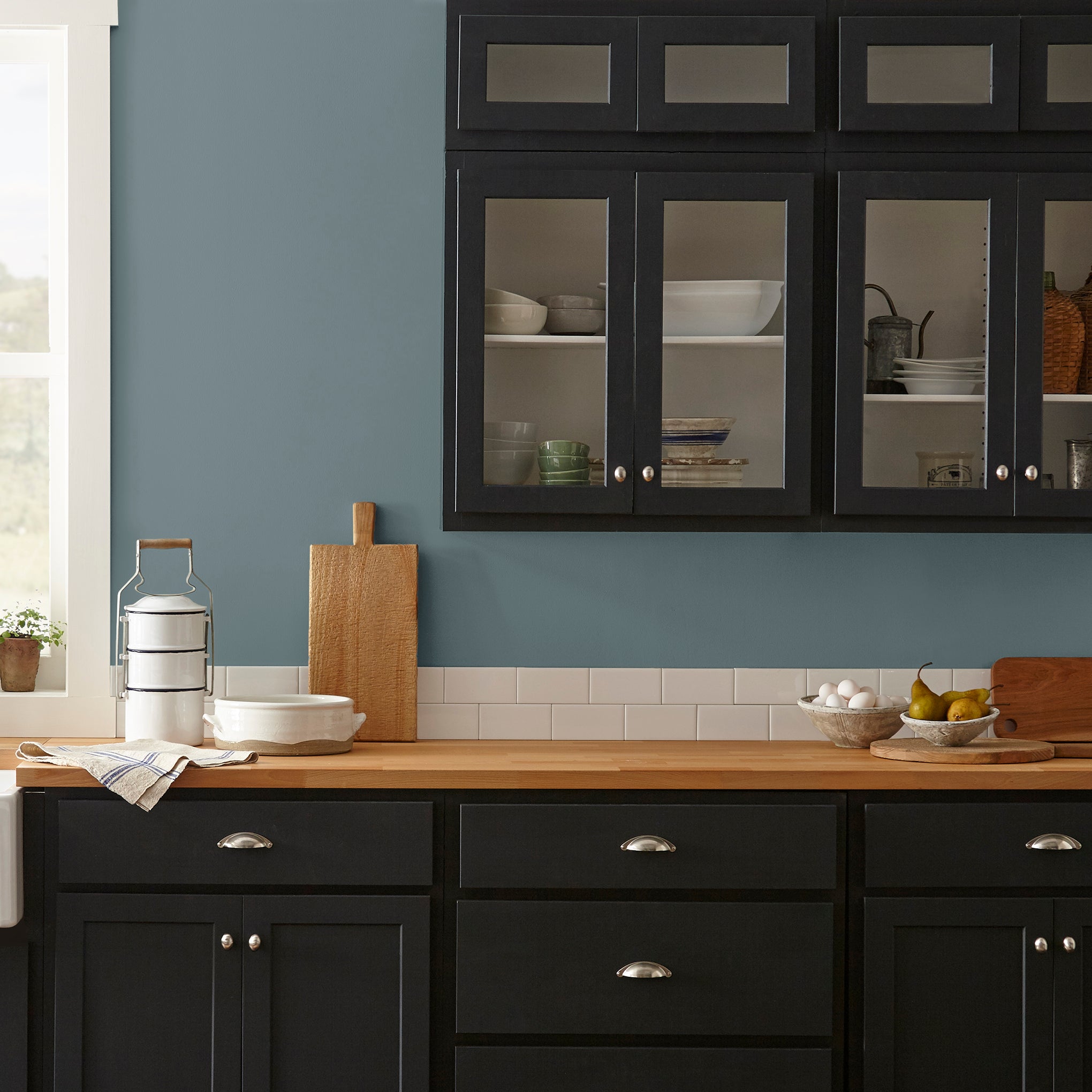 A grayed out blue interior paint named storm chaser shown painted on kitchen wall 