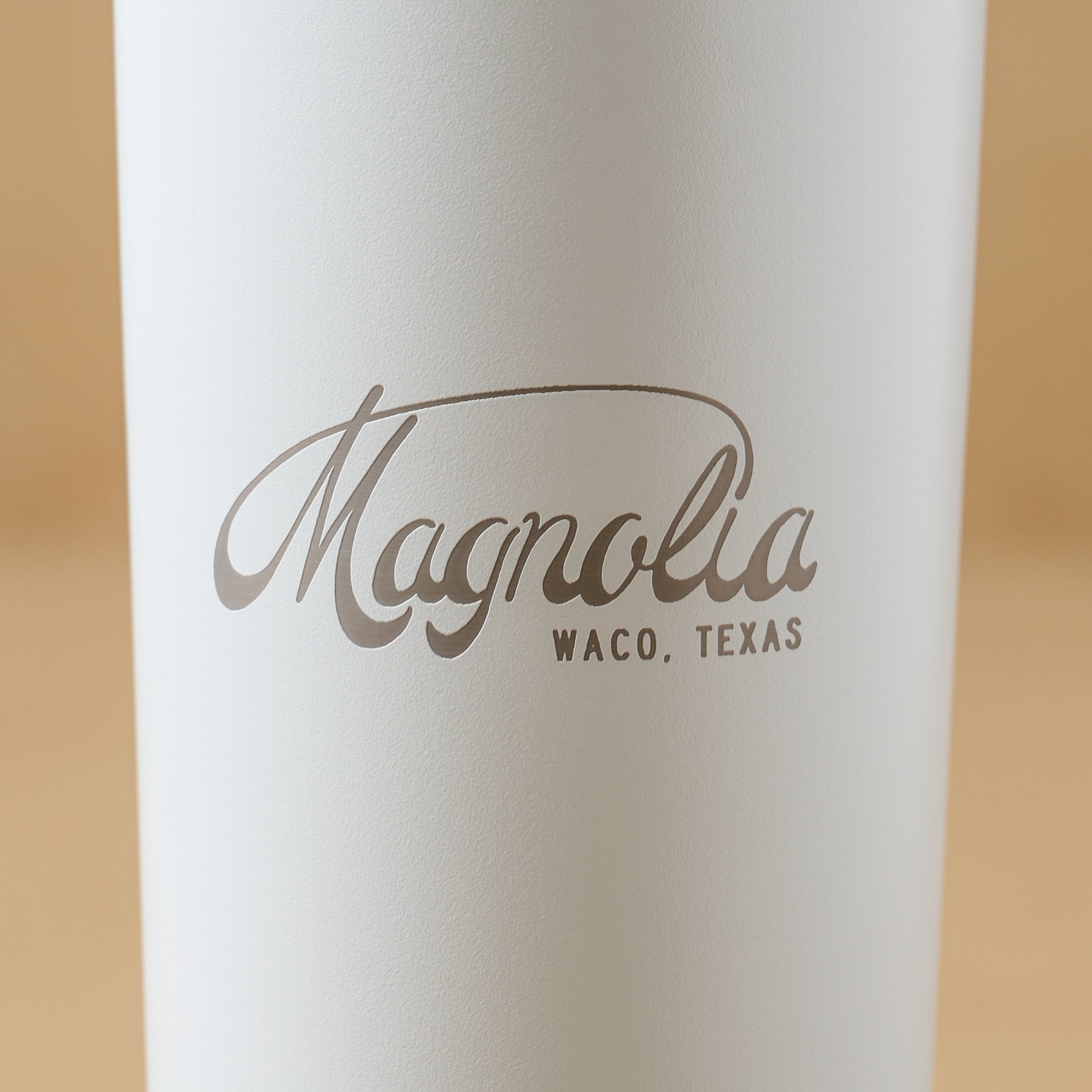 Magnoliass White 24oz Cold Tumbler with Straw close up of Magnoliass logo on cup