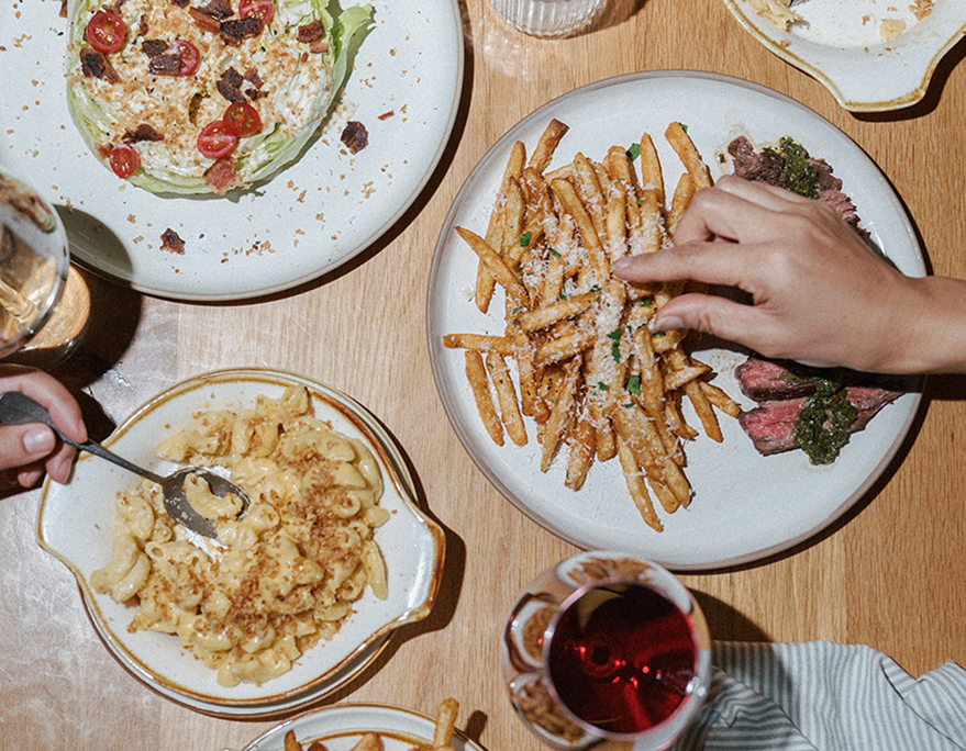 Dinner table with plates of food including fries, salad, and macaroni and cheese.