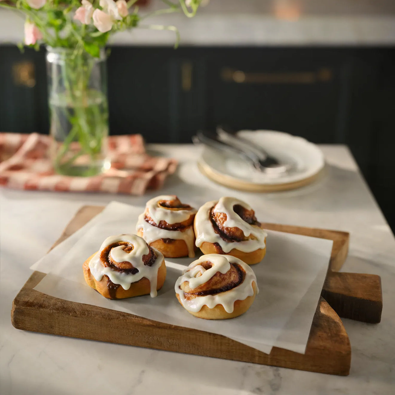Magnoliass Table Classic Cinnamon Rolls with cream cheese icing on a wooden board.