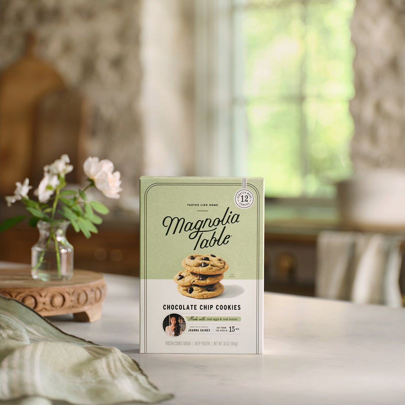 Box of Frozen Magnoliass Table Chocolate Chip Cookie Dough on a table with flowers in the background.