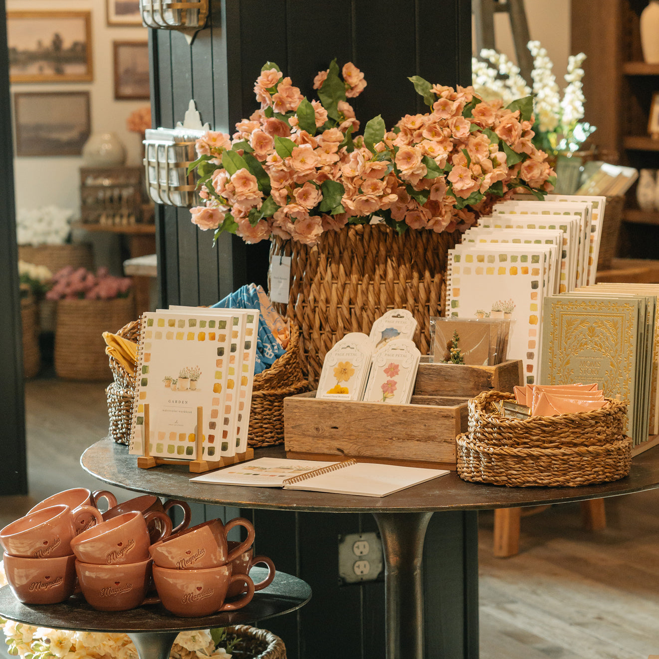 Table with decorative items including flowers, baskets, and mugs in Magnoliass Market.