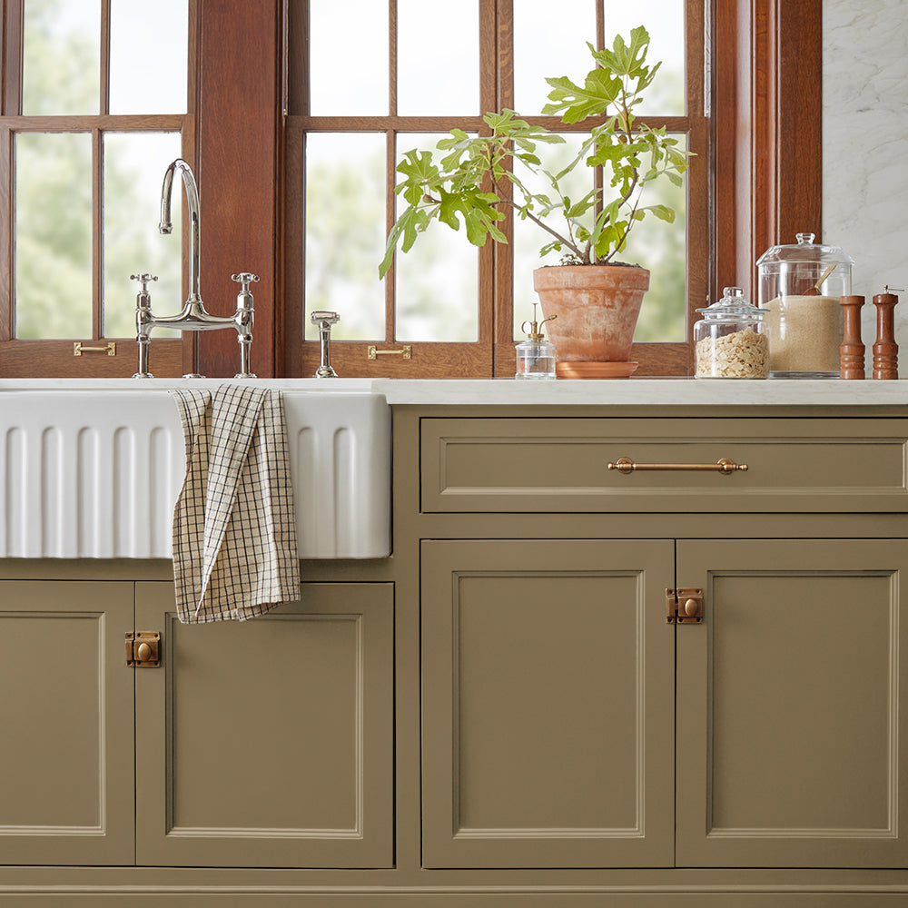 rich green with brown undertone paint color named remote trail shown painted on kitchen cabinet