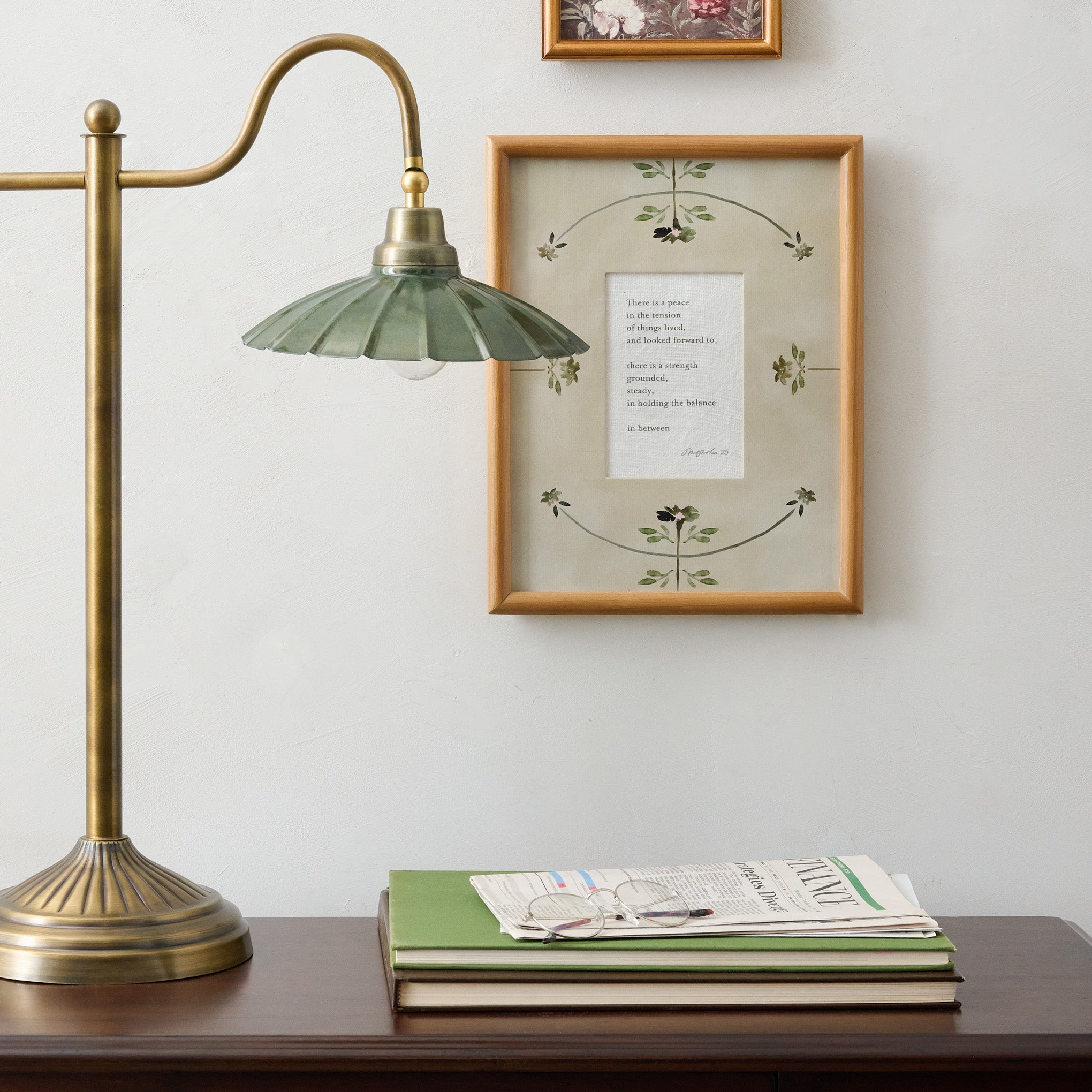 The Balance in Between Framed Poem shown hung on wall by desk and table lamp