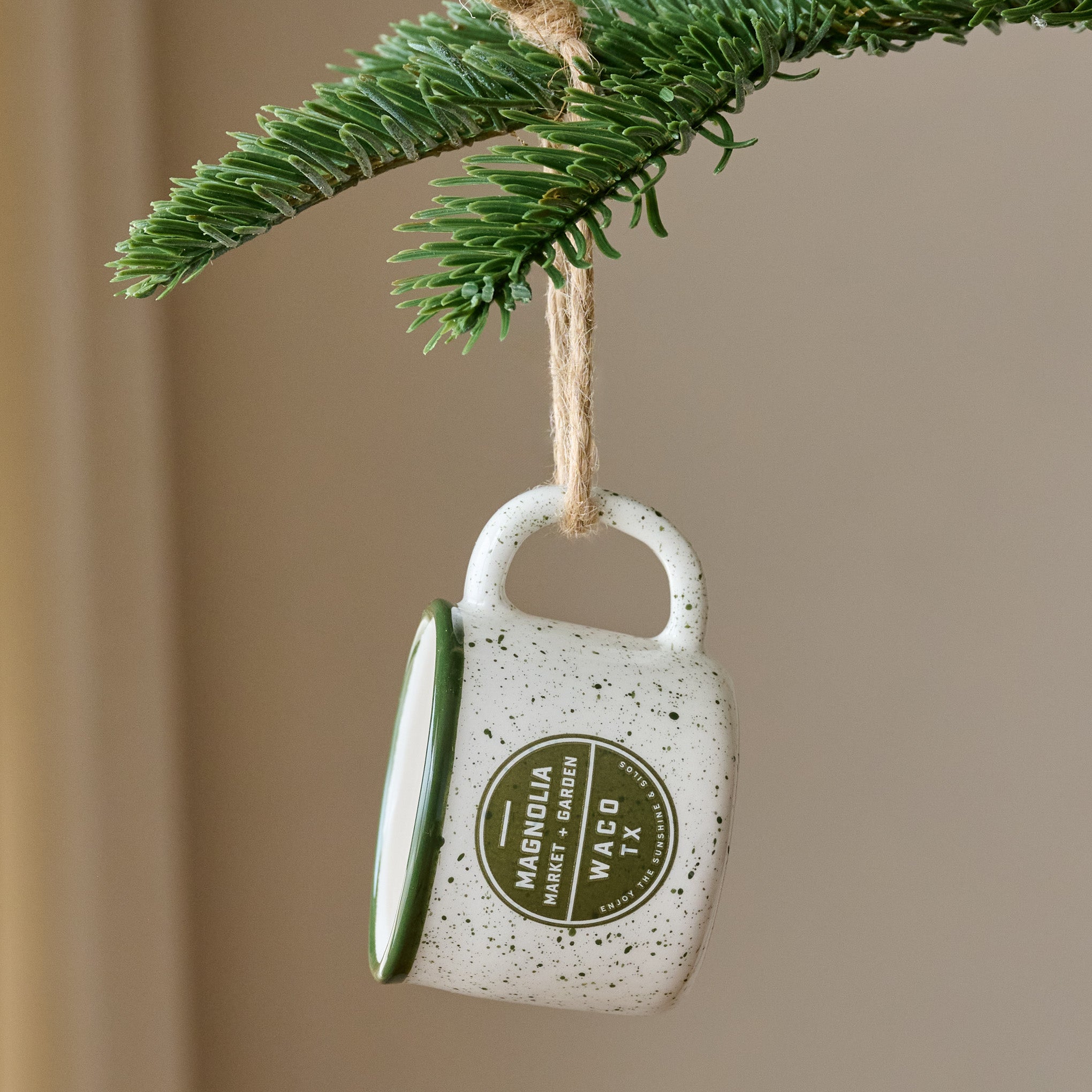 Green Magnoliass Campfire Mug Ornament shown hung from tree