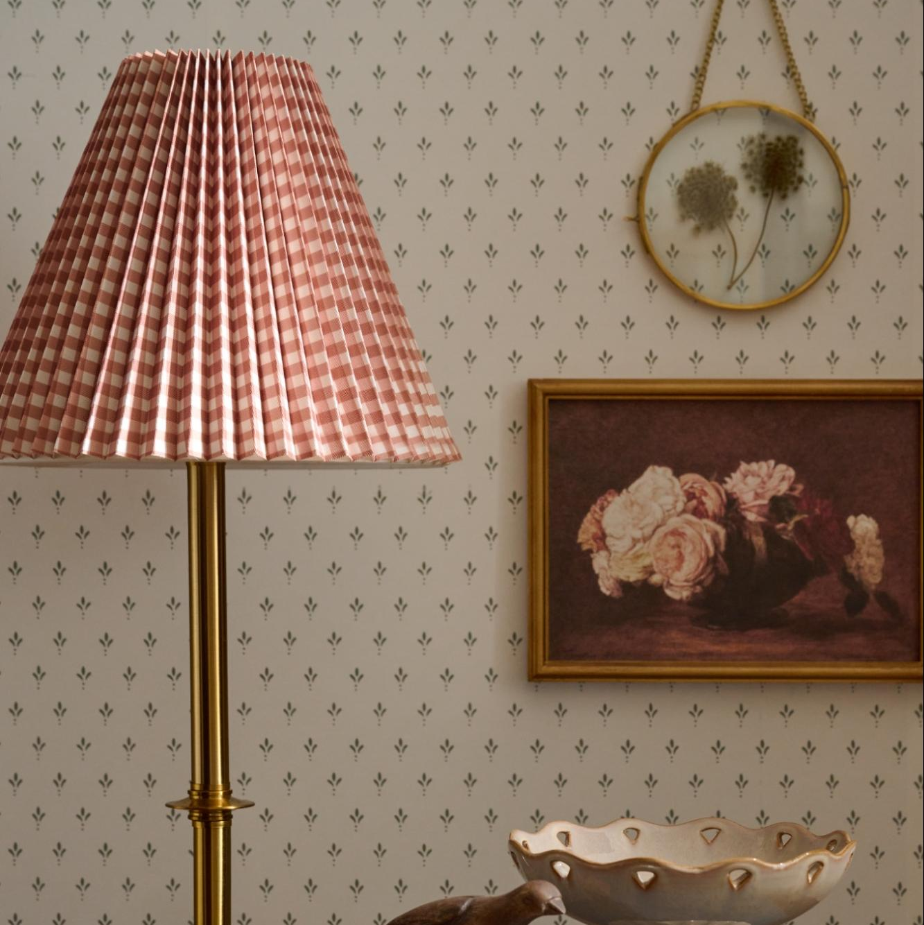 Decorative interior with a lamp, wall art, and decorative items on patterned wallpaper.