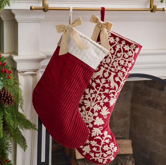 Red Christmas stockings with white patterns hanging on a fireplace mantle.