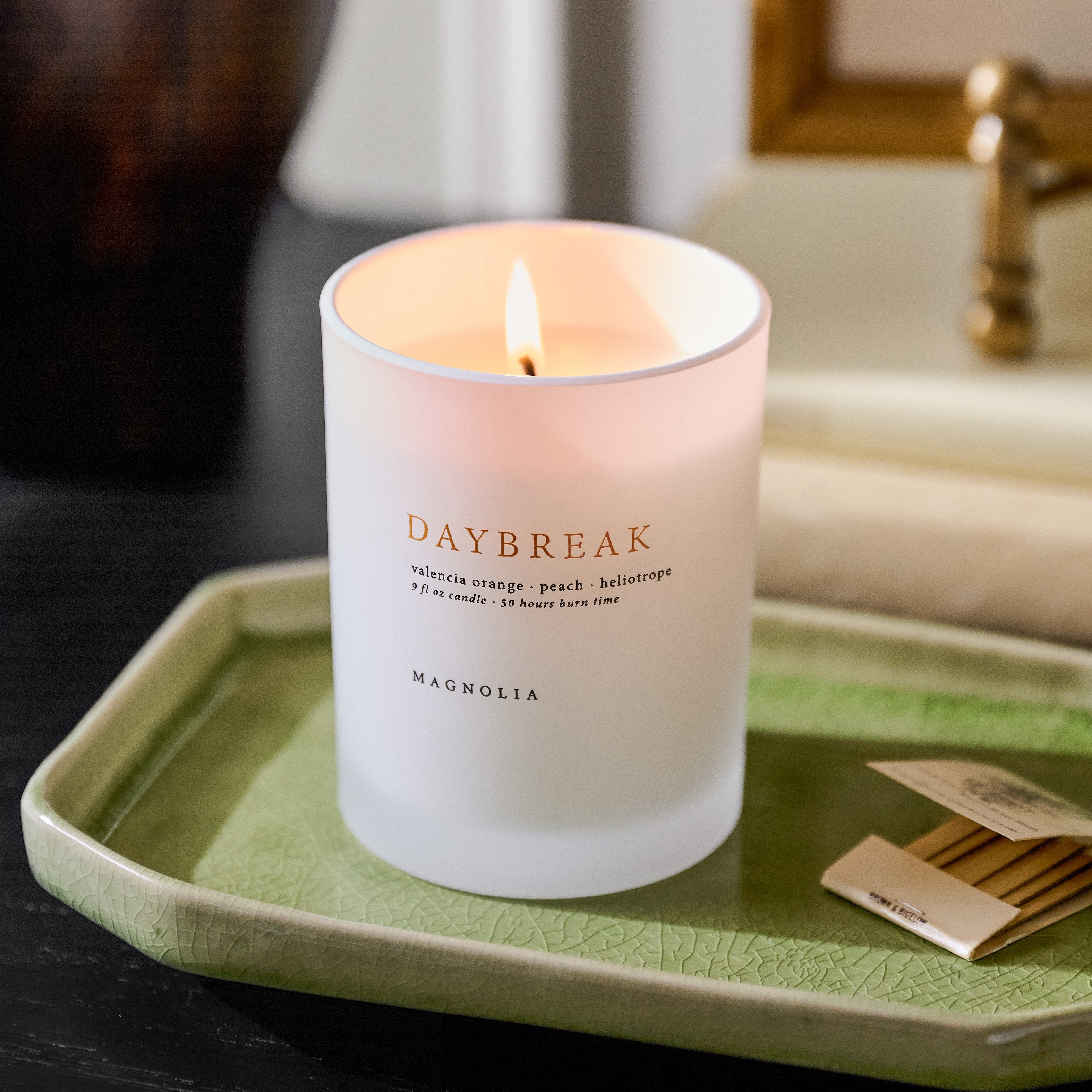 Magnoliass Daybreak Candle on a green ceramic tray with match book