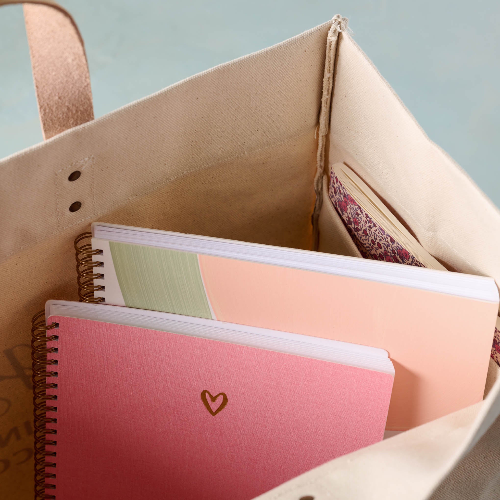 close up of Magnoliass Cora Script Large Canvas Tote containing pink heart notebook and melon sketchbook