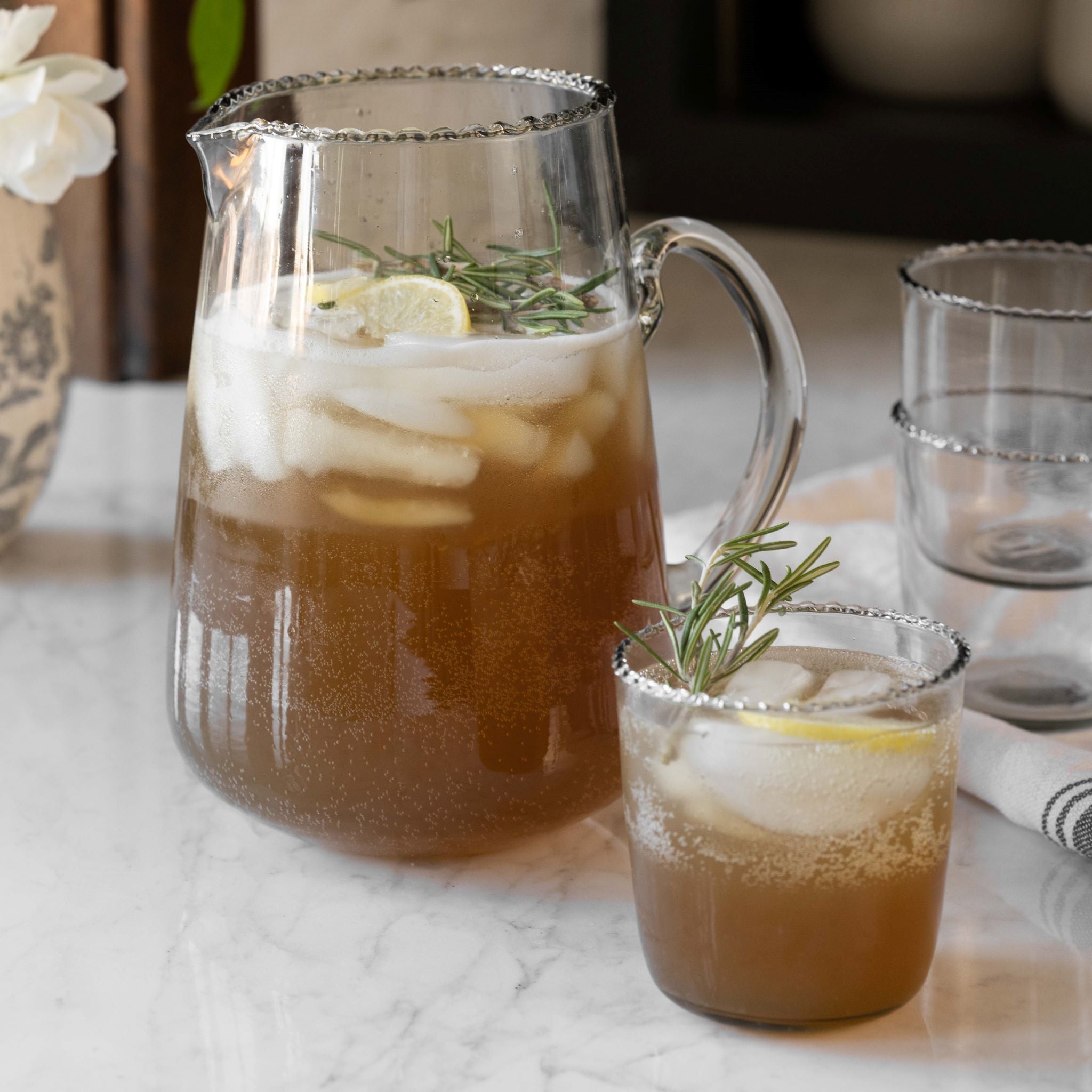 Elizabeth bottle cut pitcher and elizabeth bottle cut tumbler containing lemon and rosemary tea