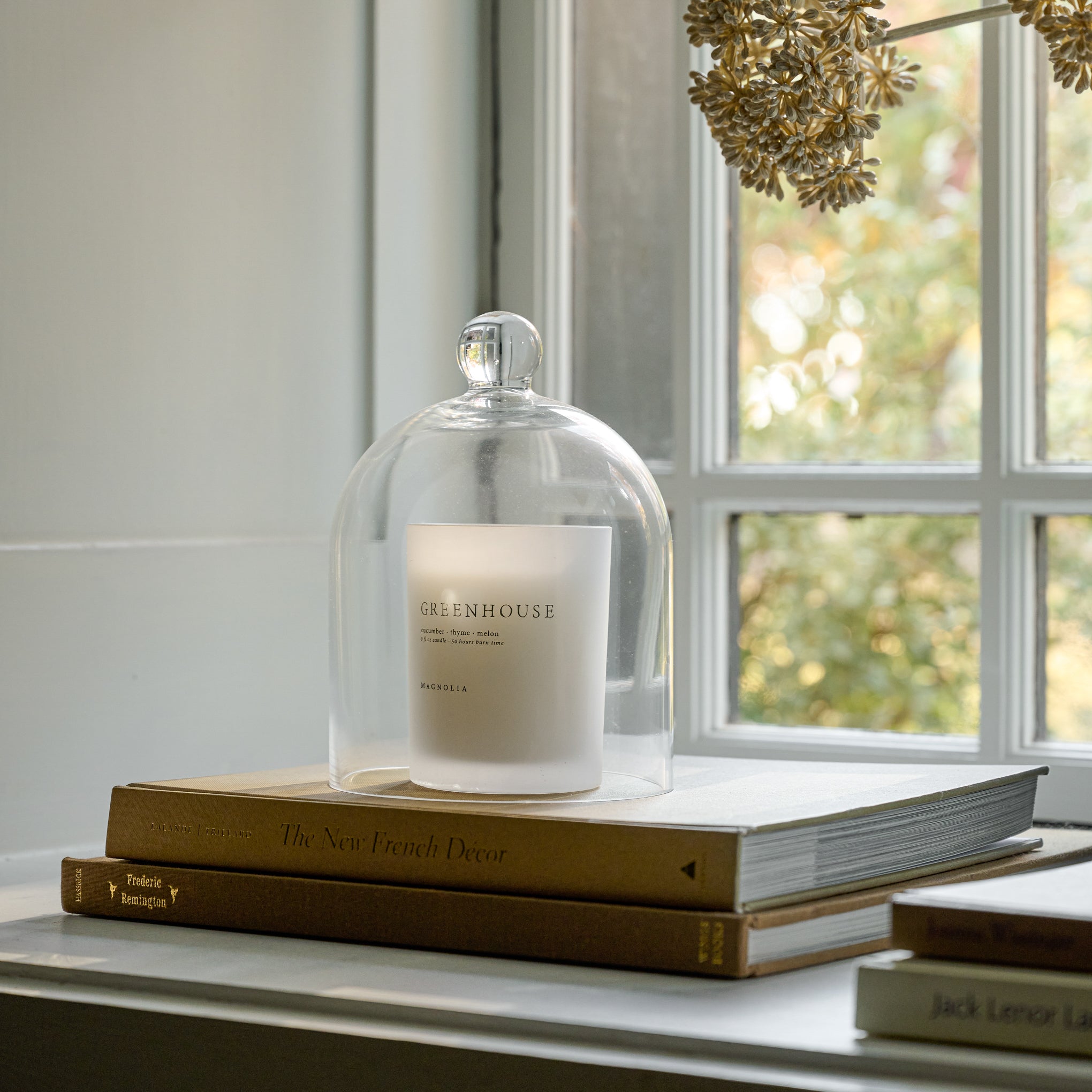 Magnoliass Greenhouse Candle on books in window sill
