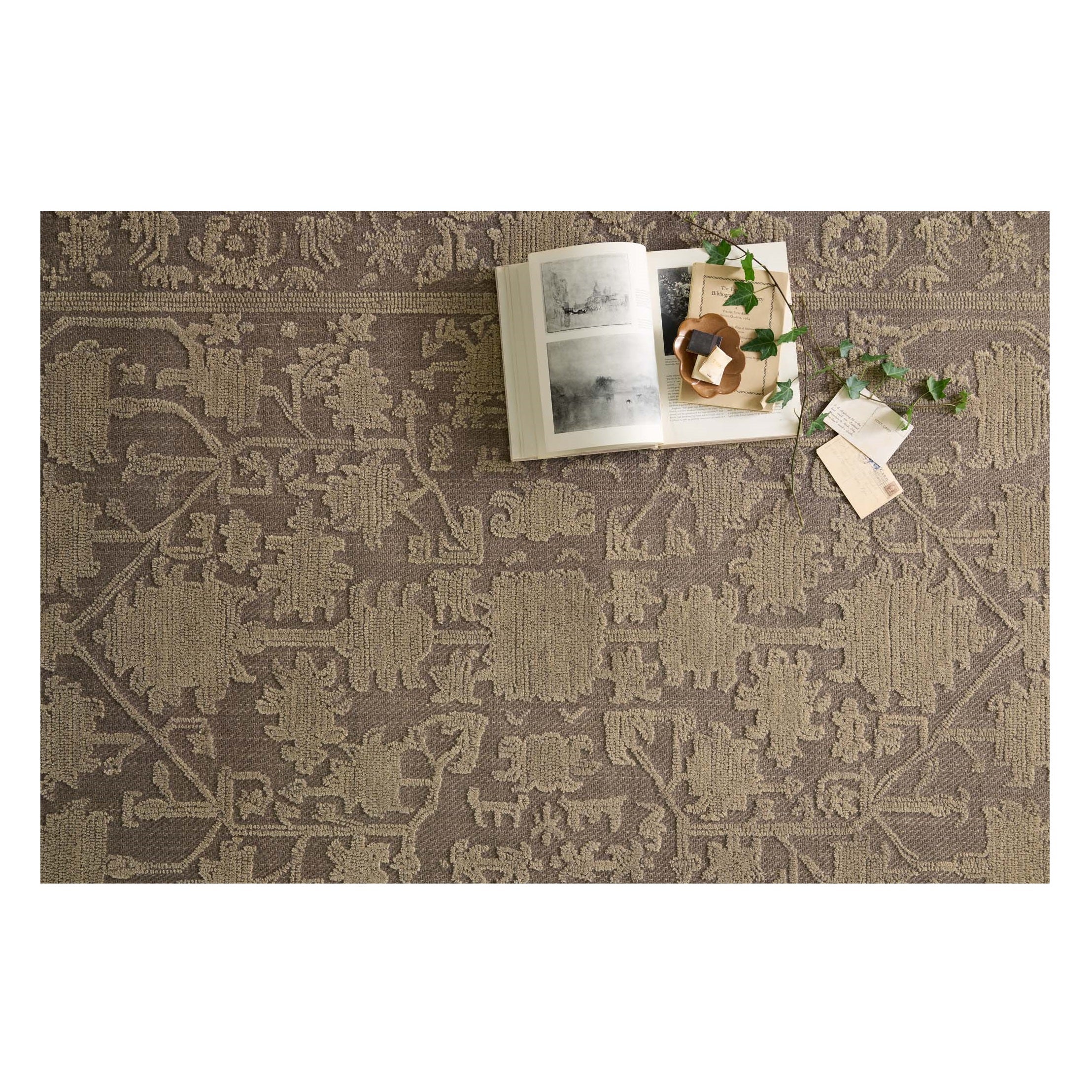 Gloria Bark Khaki Rug with a book and greenery on it