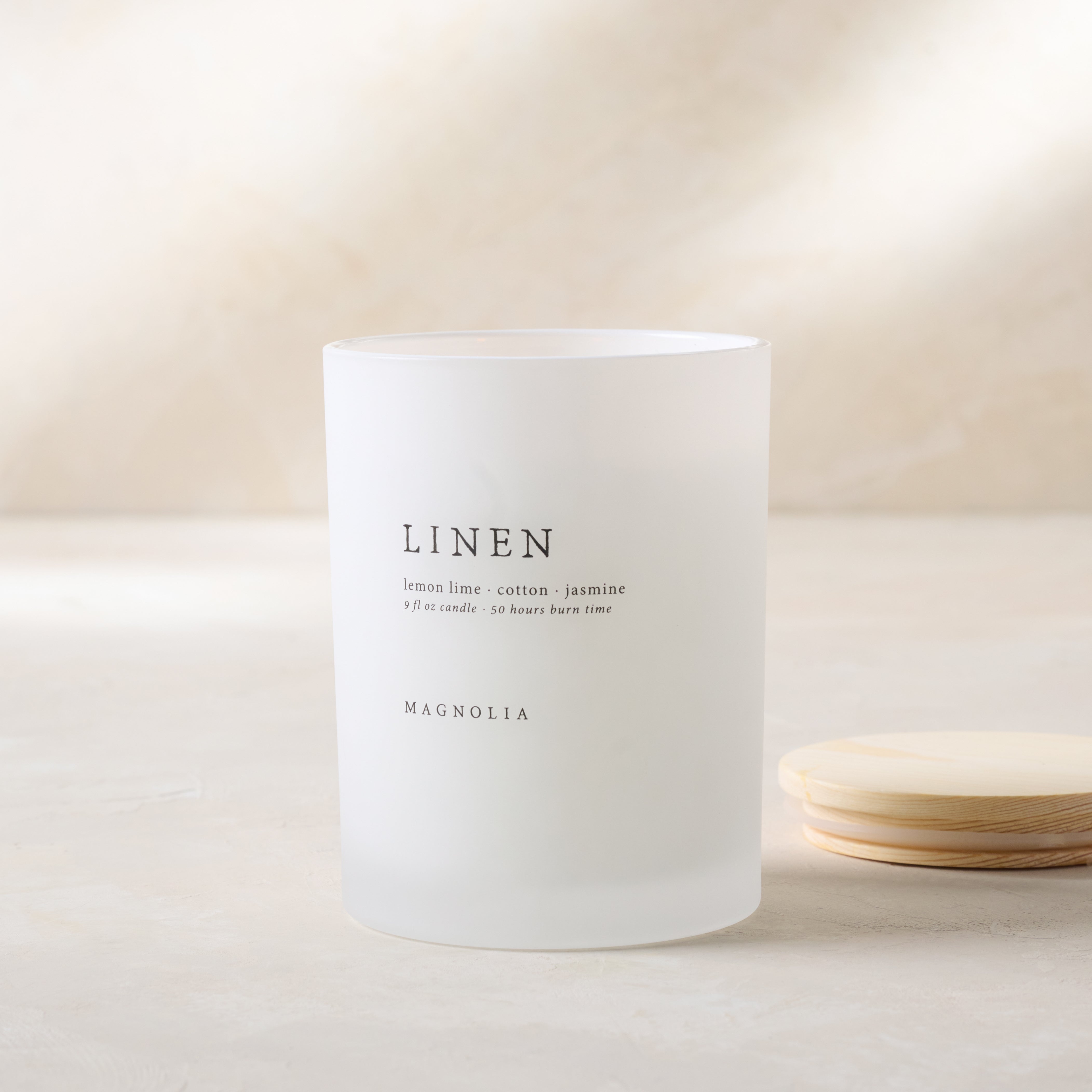 Magnoliass linen candle with wood lid notes scents of lemon lime cotton and jasmine