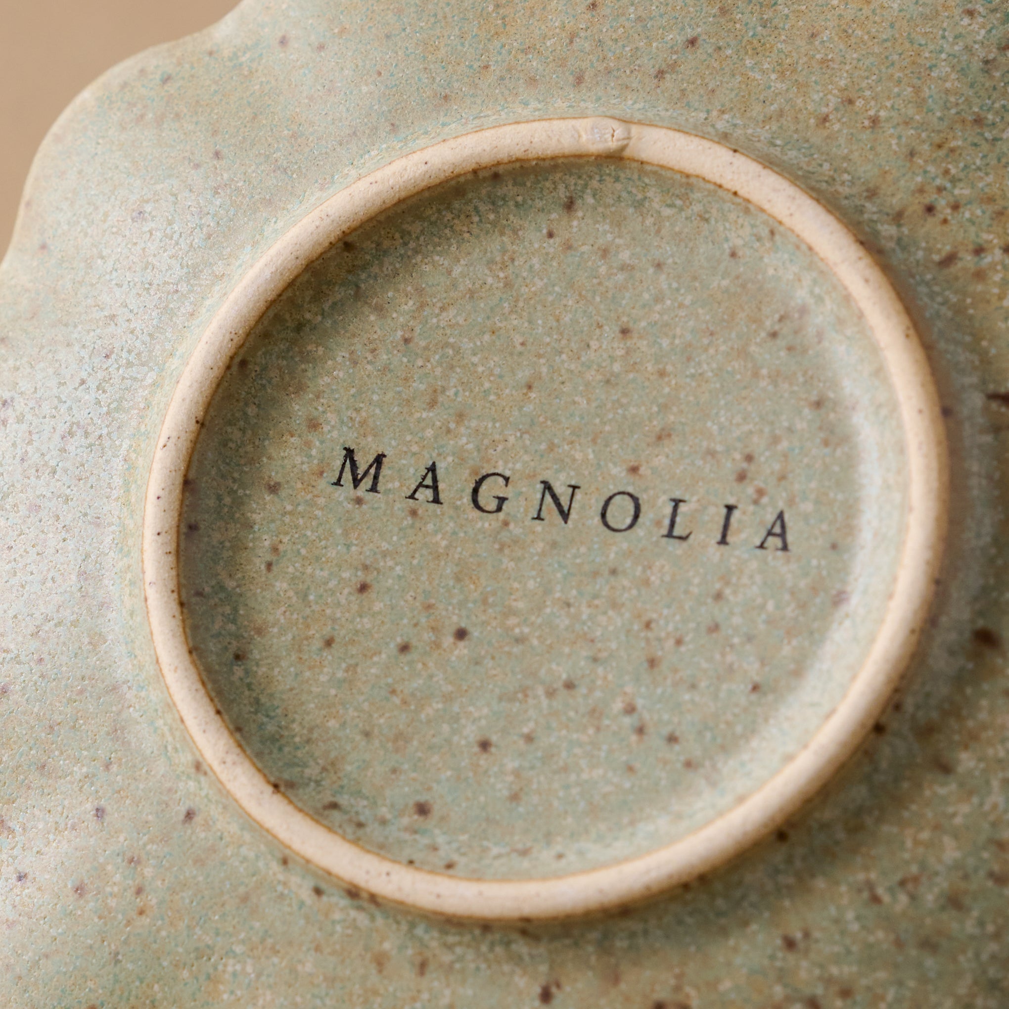 Close up of Magnoliass logo on bottom of Scalloped Edge Stoneware Coaster 