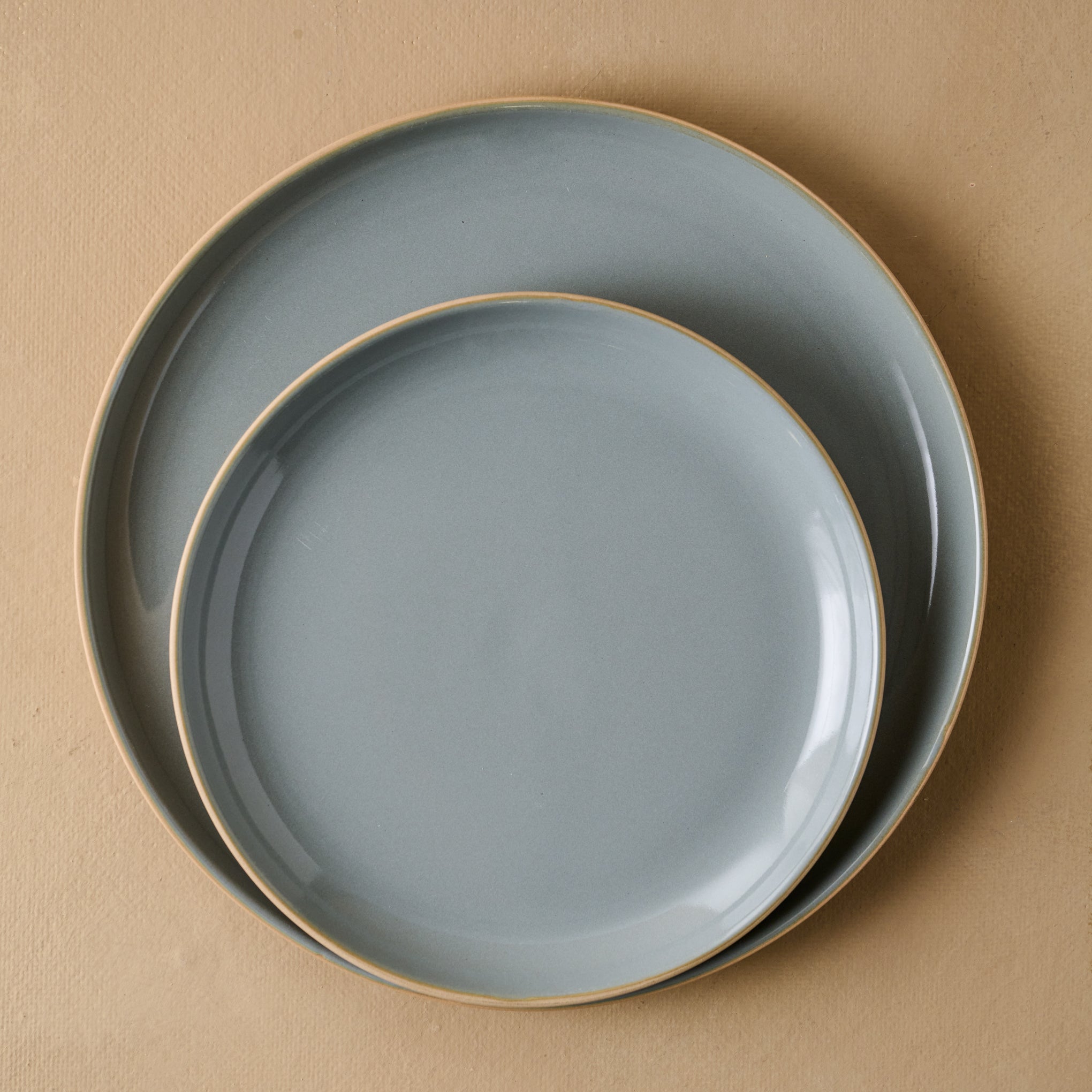 Lakelynn plates with a glazed blue gray interior and a tan exterior stacked atop one another. 