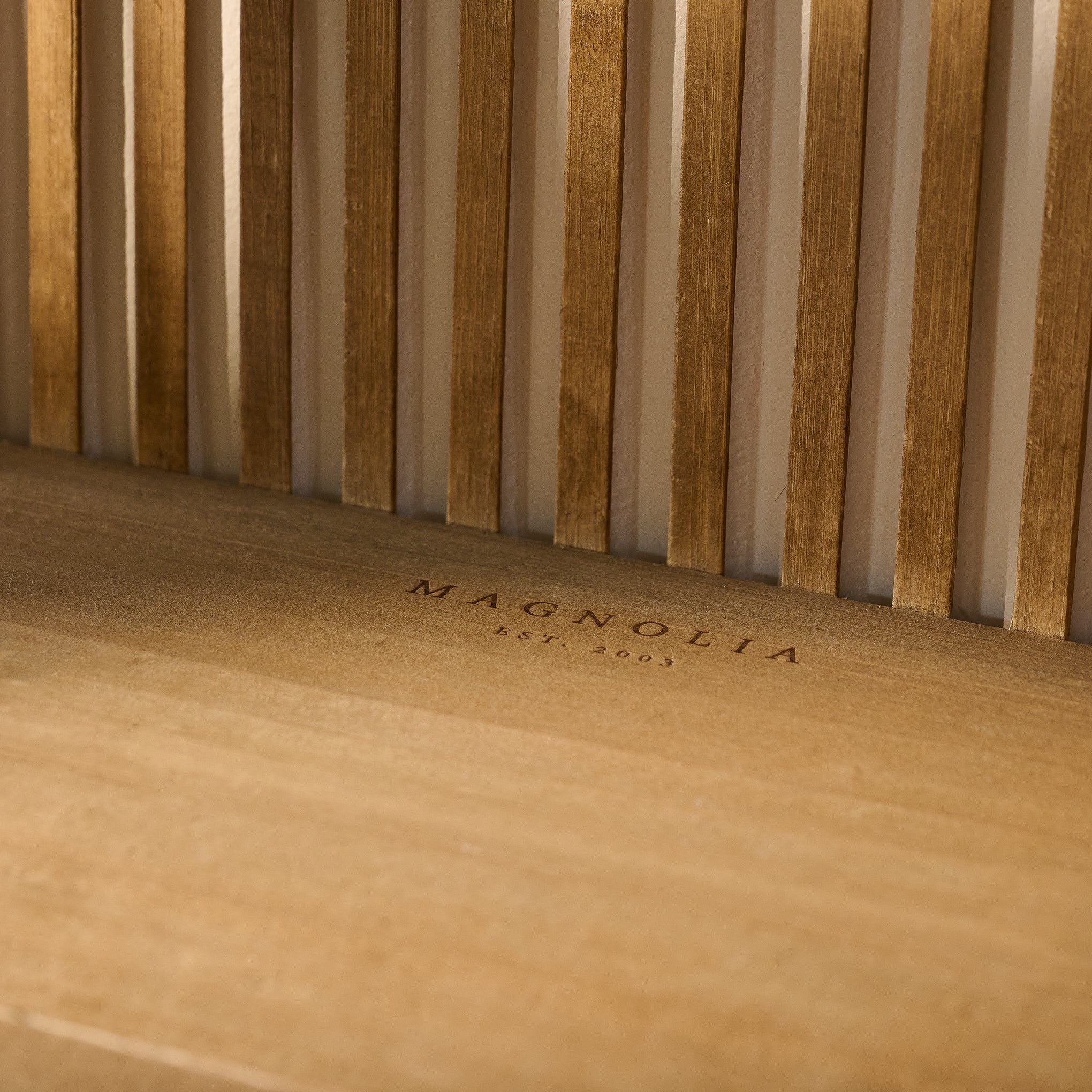 Close up of Magnoliass logo embossed on shelf of Preston Reeded Wall Shelf