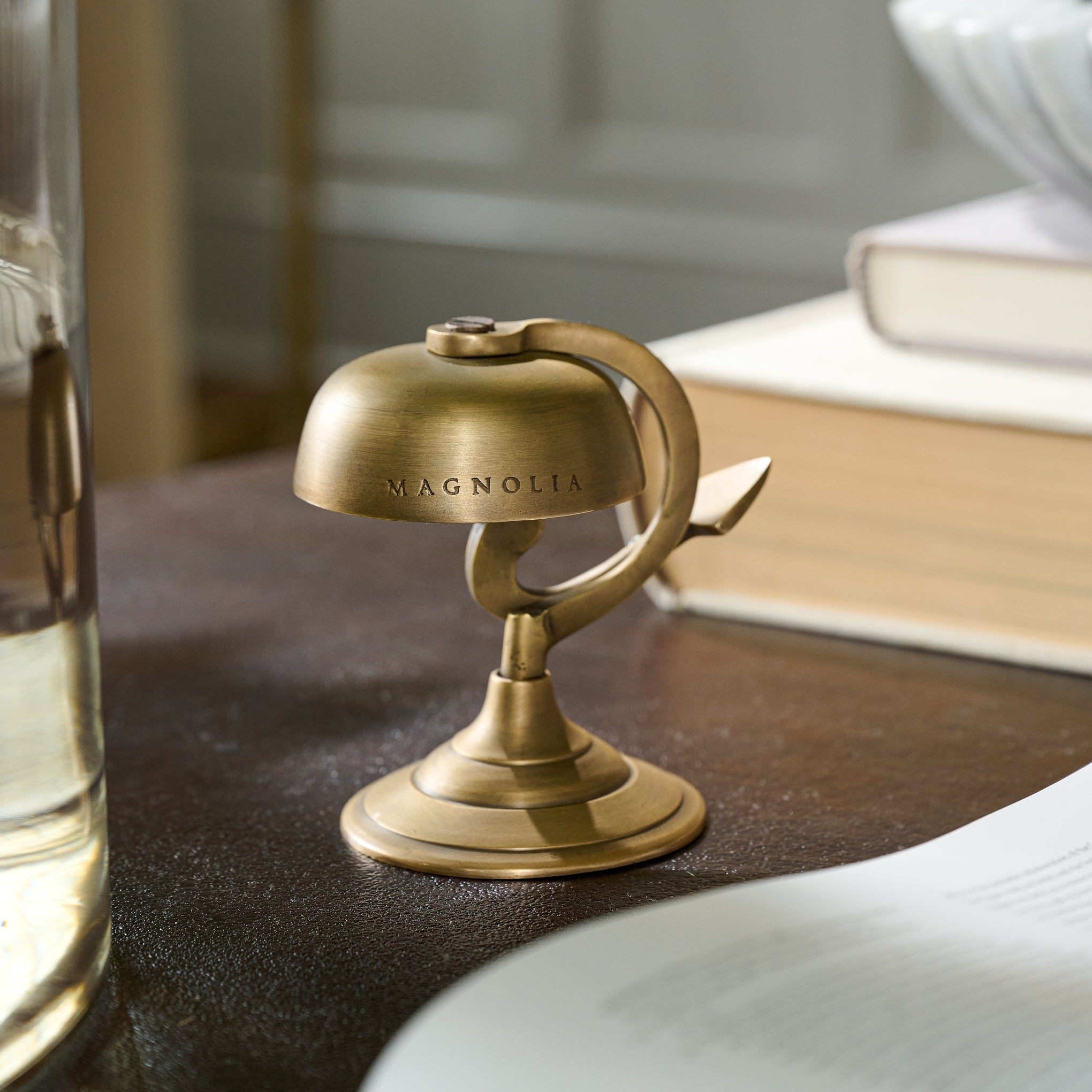 Antique Brass Bell engraved with Magnoliass logo on a desk 