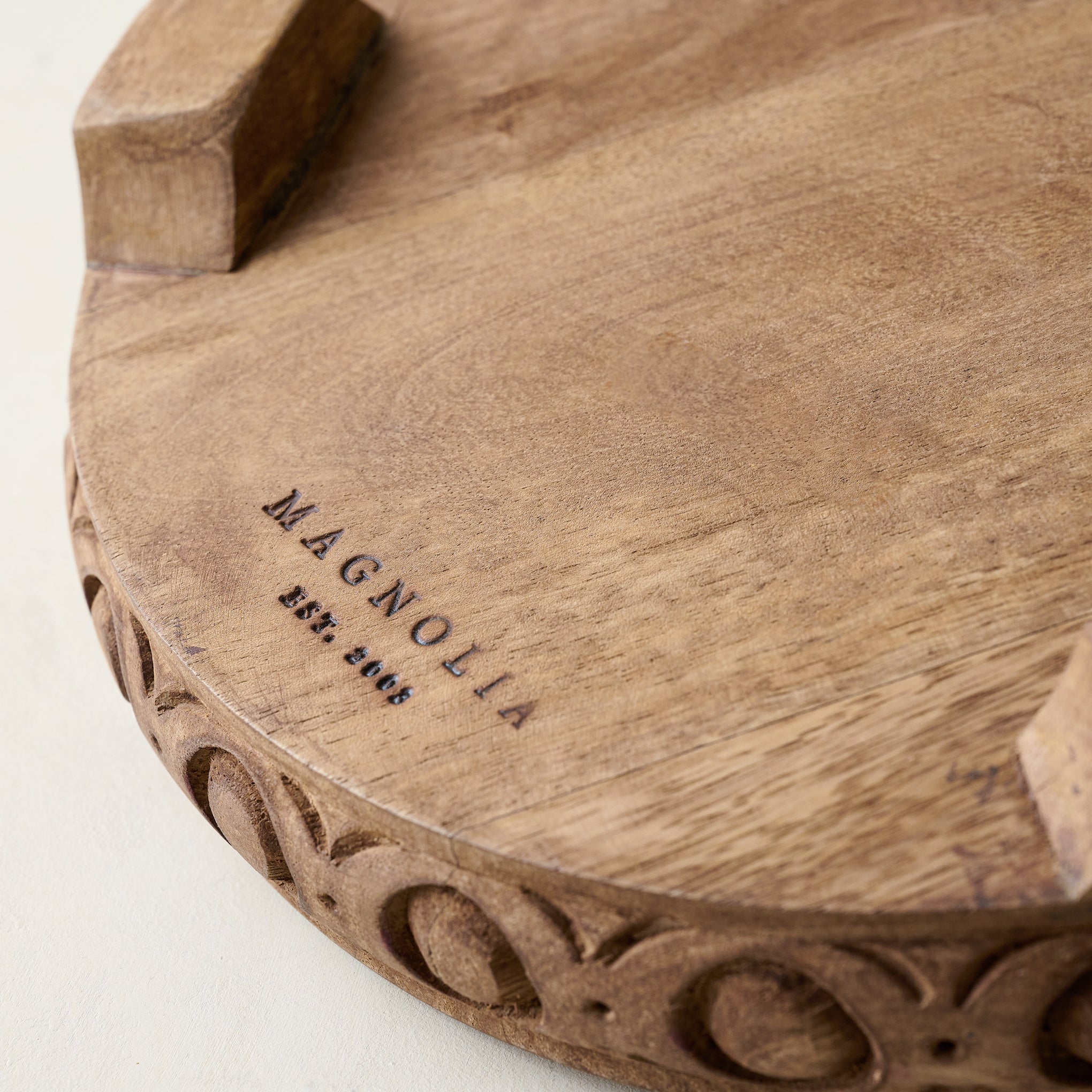 Antiqued Carved Wood Round Riser Magnoliass logo on the bottom