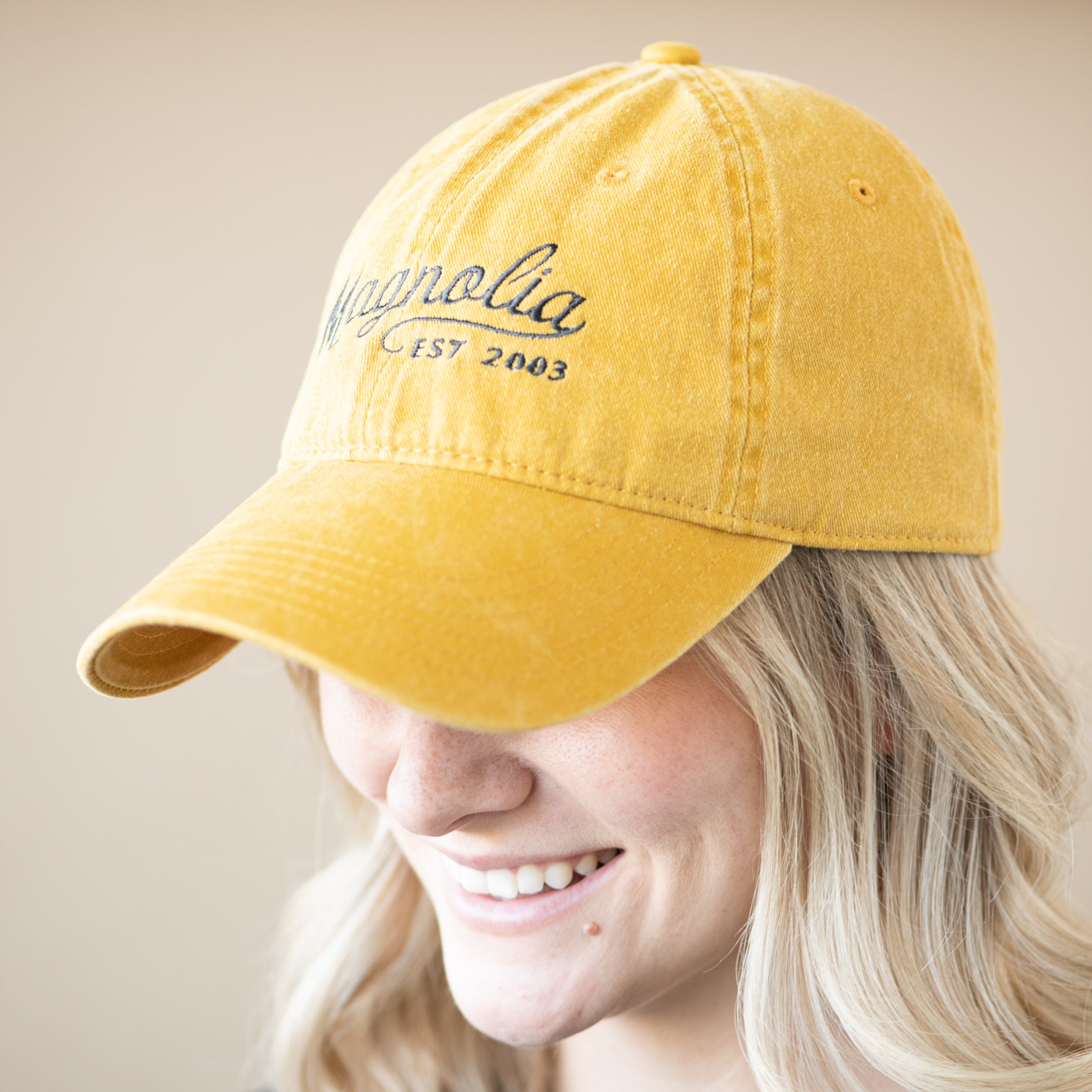yellow ball cap with "Magnolia Est 2003" in cursive script