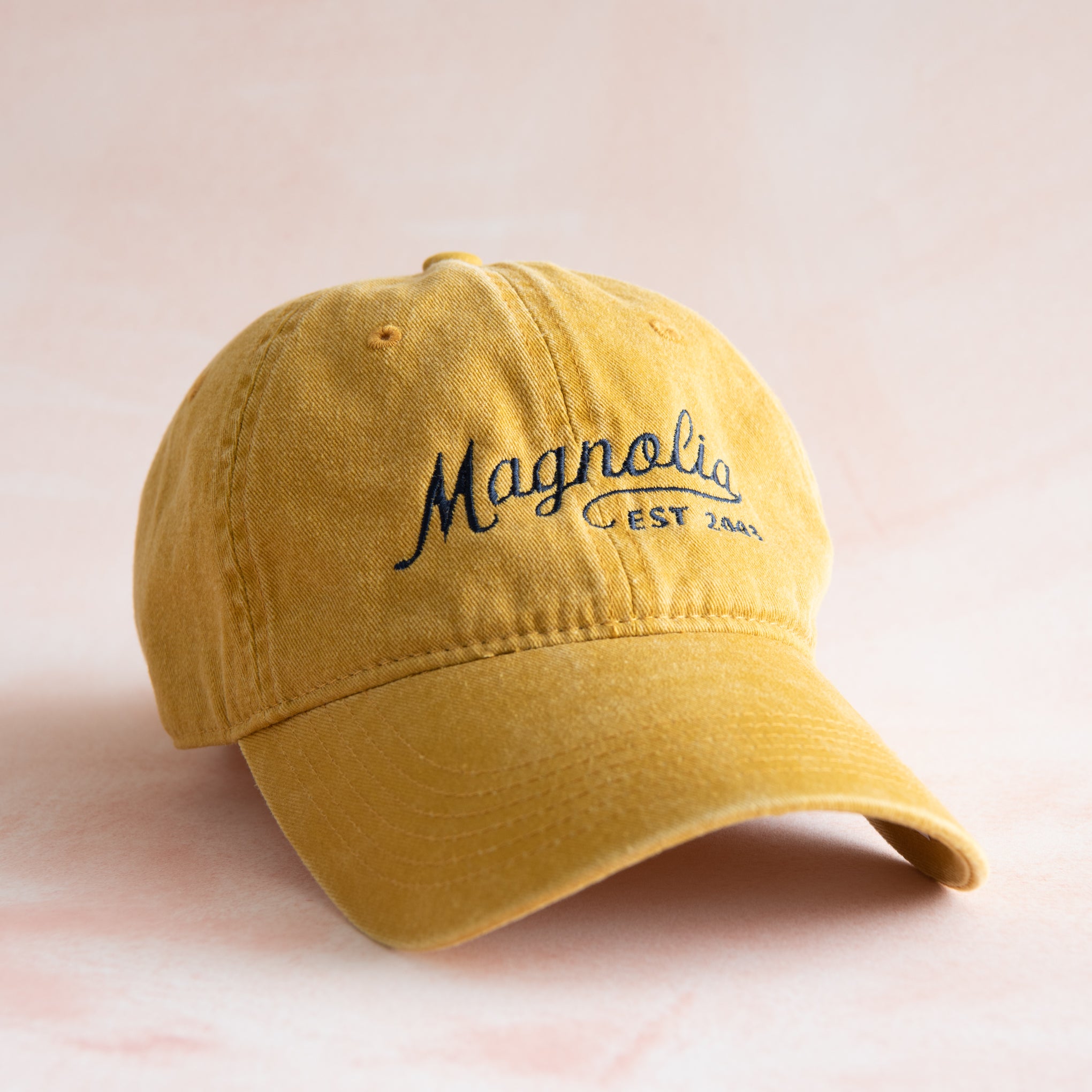 yellow ball cap with "Magnolia Est 2003" in cursive script