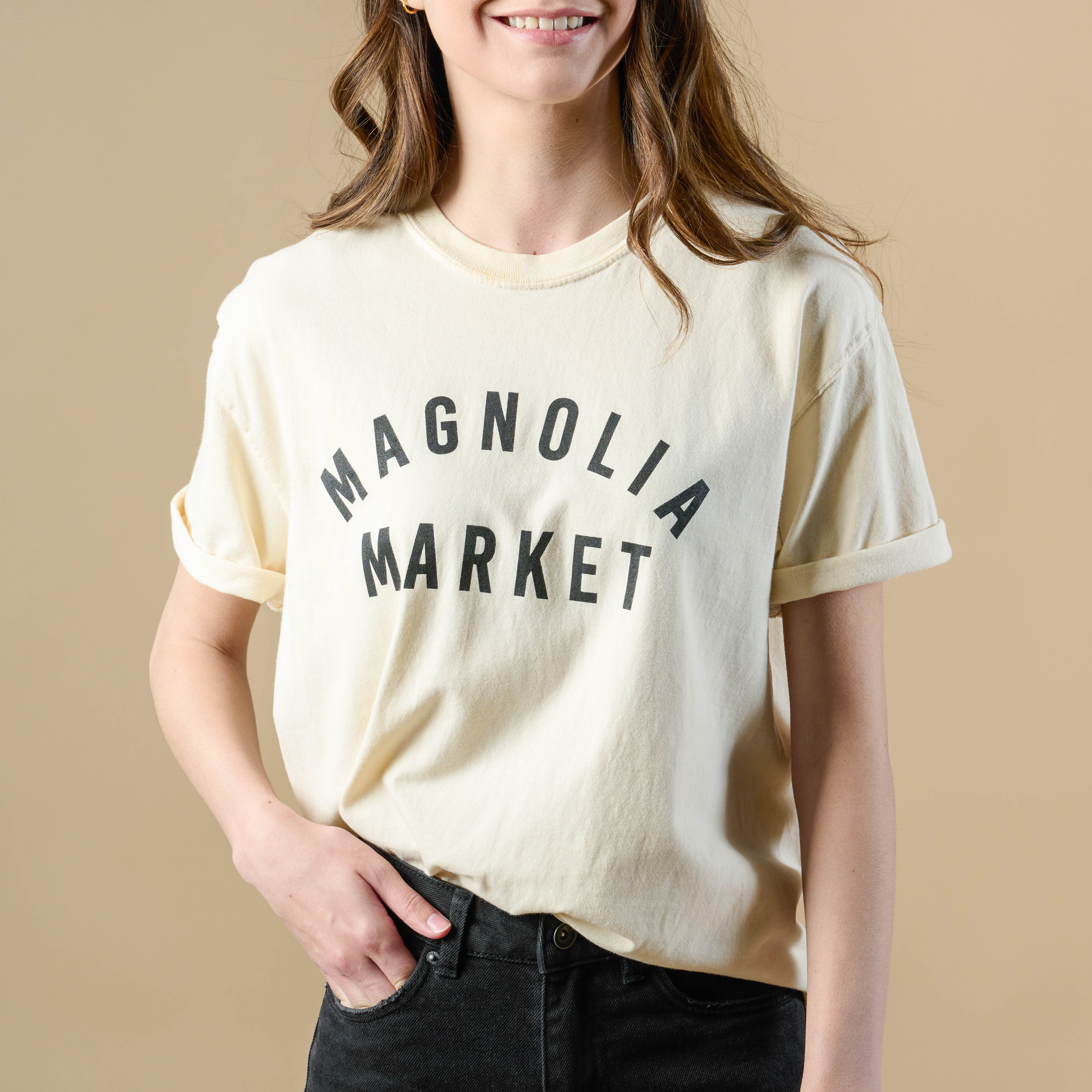Model wearing Magnoliass market ivory shirt that reads Magnoliass Market in plain black text.