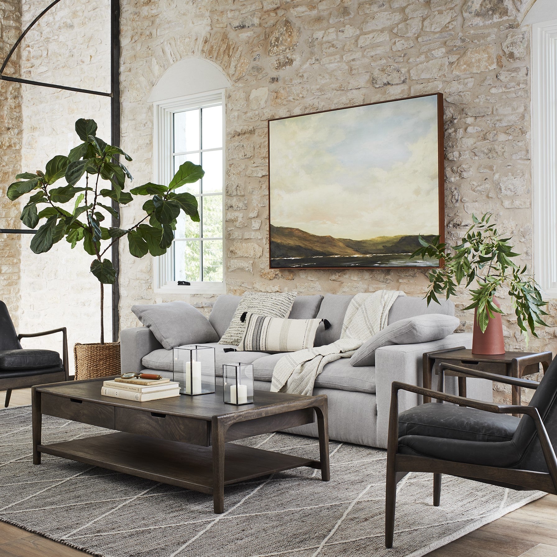 Framed wall art called the hills at dusk hanging over sofa on stone wall