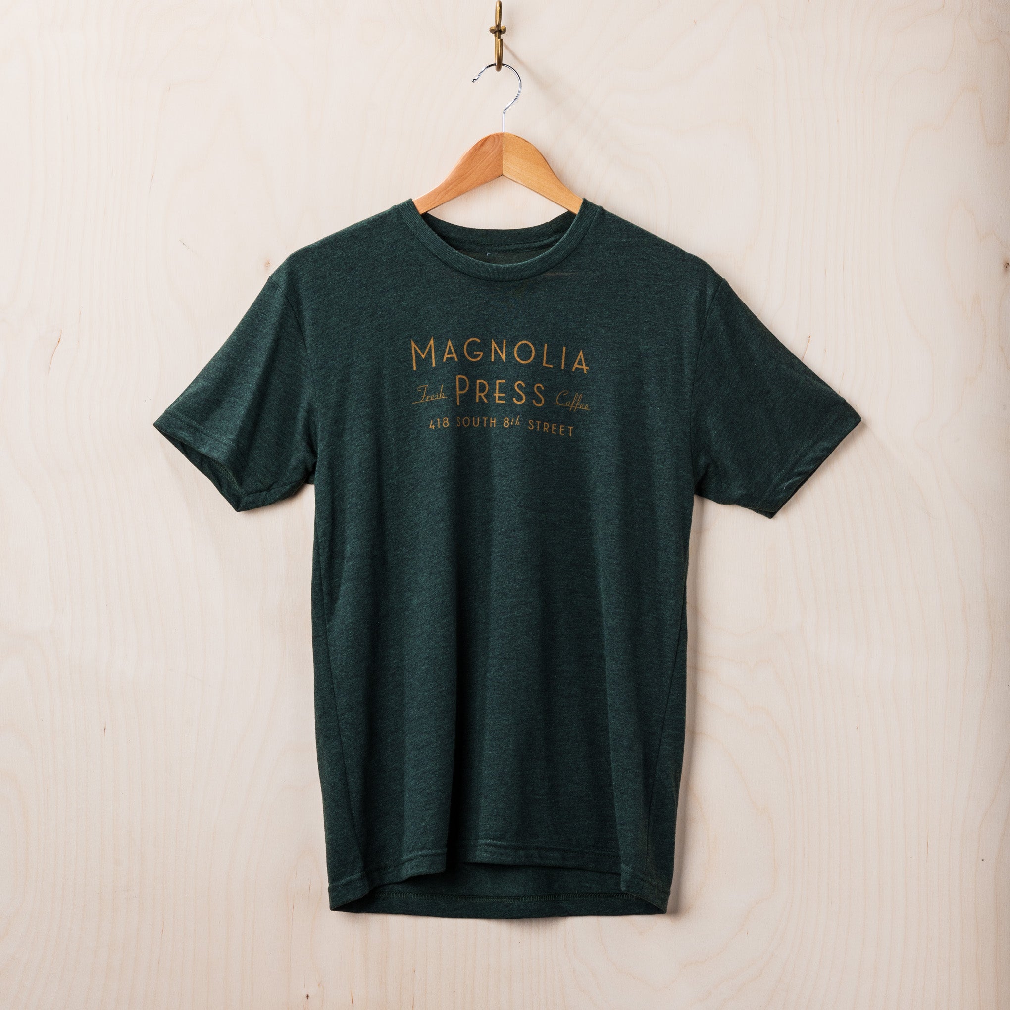 emerald green t-shirt with Magnoliass press coffee logo in gold across chest