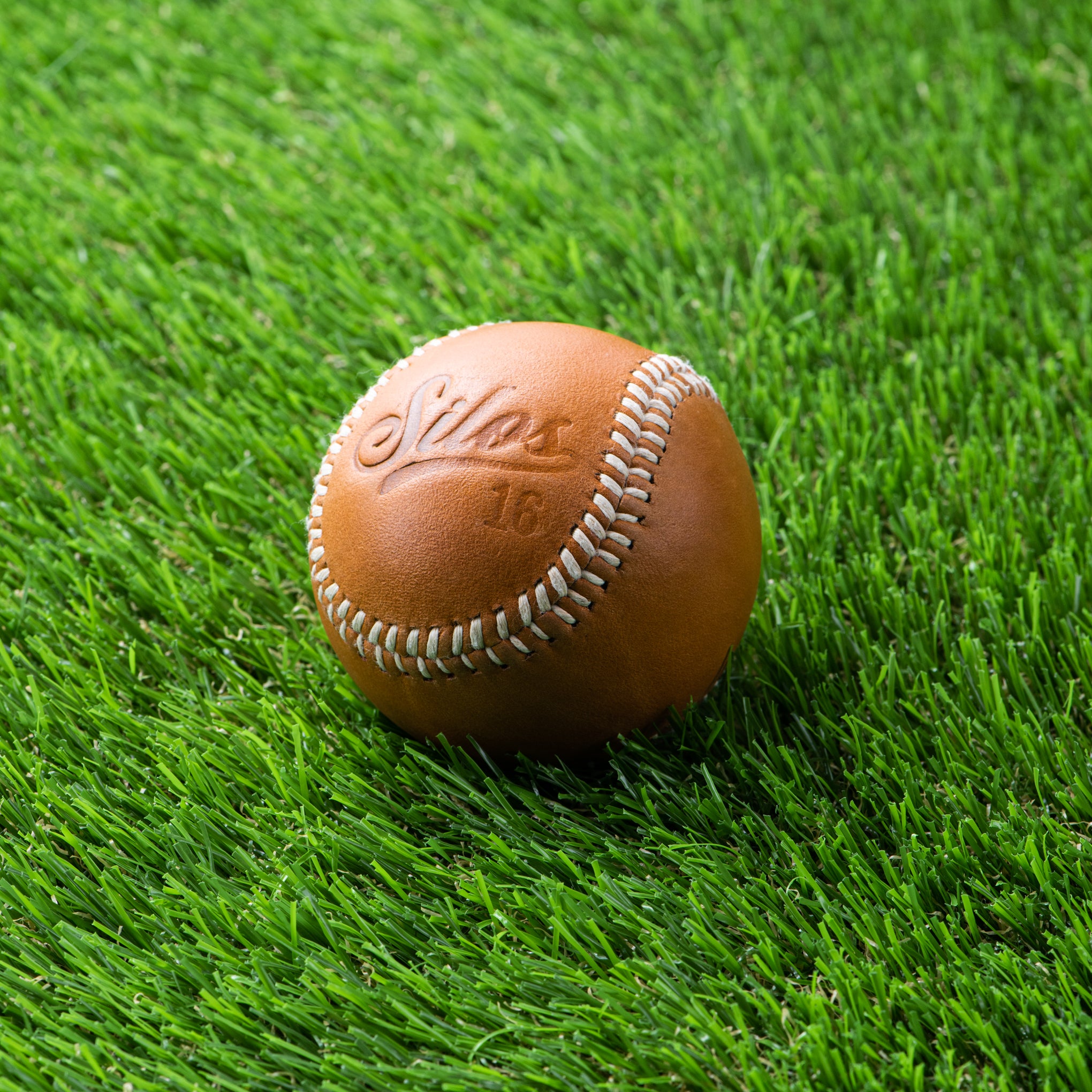 tan leather baseball with silos baseball logo and Magnoliass logo on the opposite side