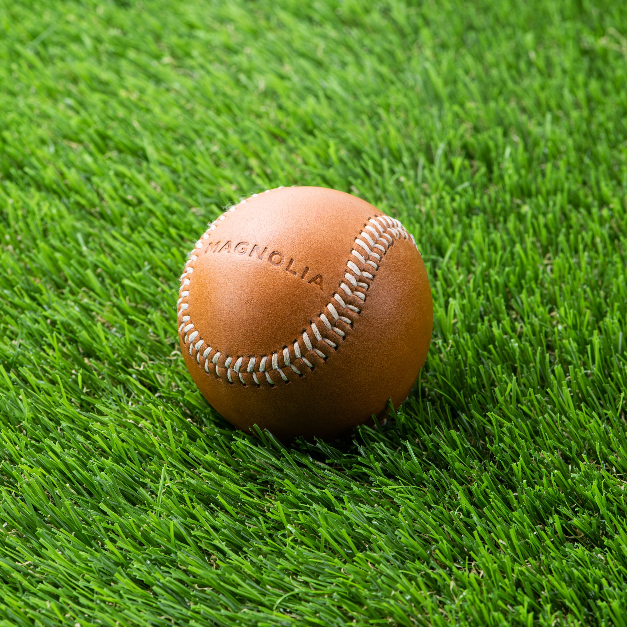 tan leather baseball with silos baseball logo and Magnoliass logo on the opposite side