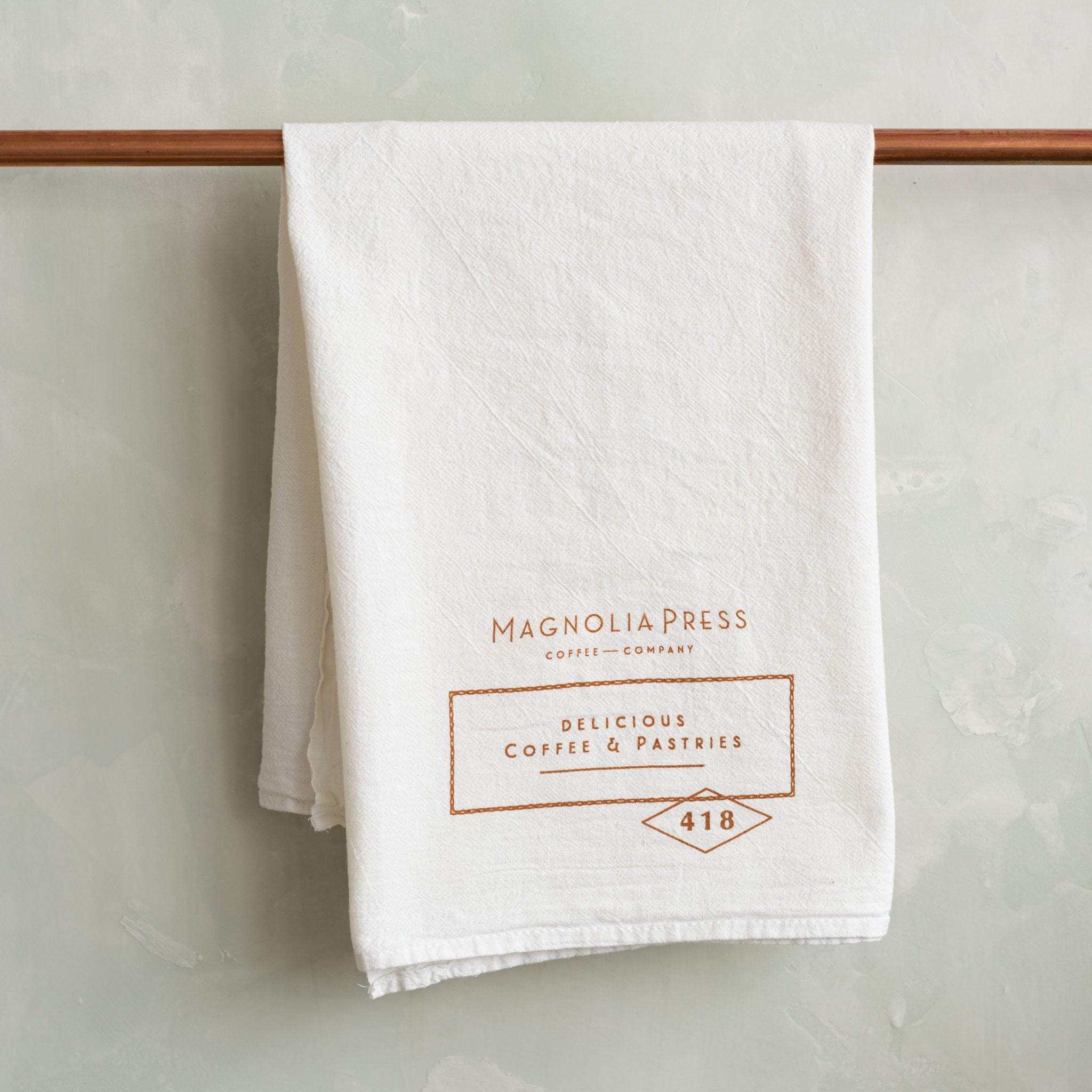 white tea towel with Magnoliass press logo in copper