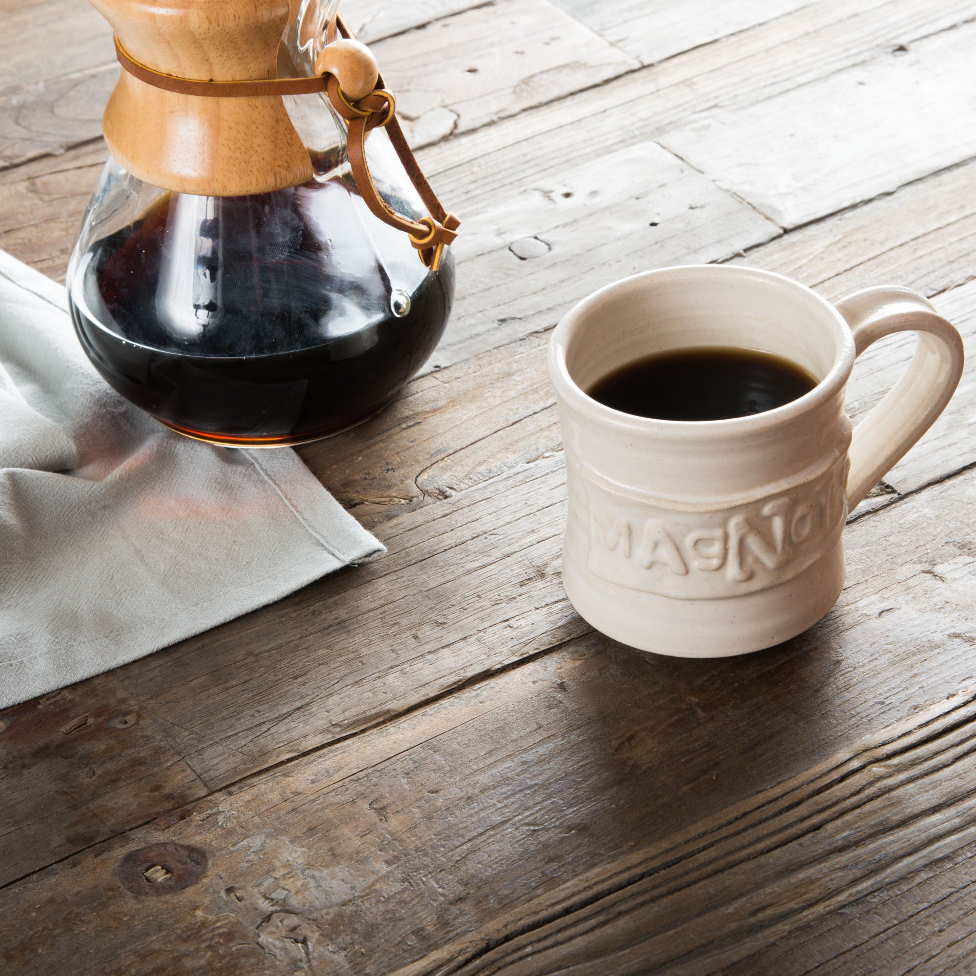 white handthrown ceramic mug with original Magnoliass logo embossed on side
