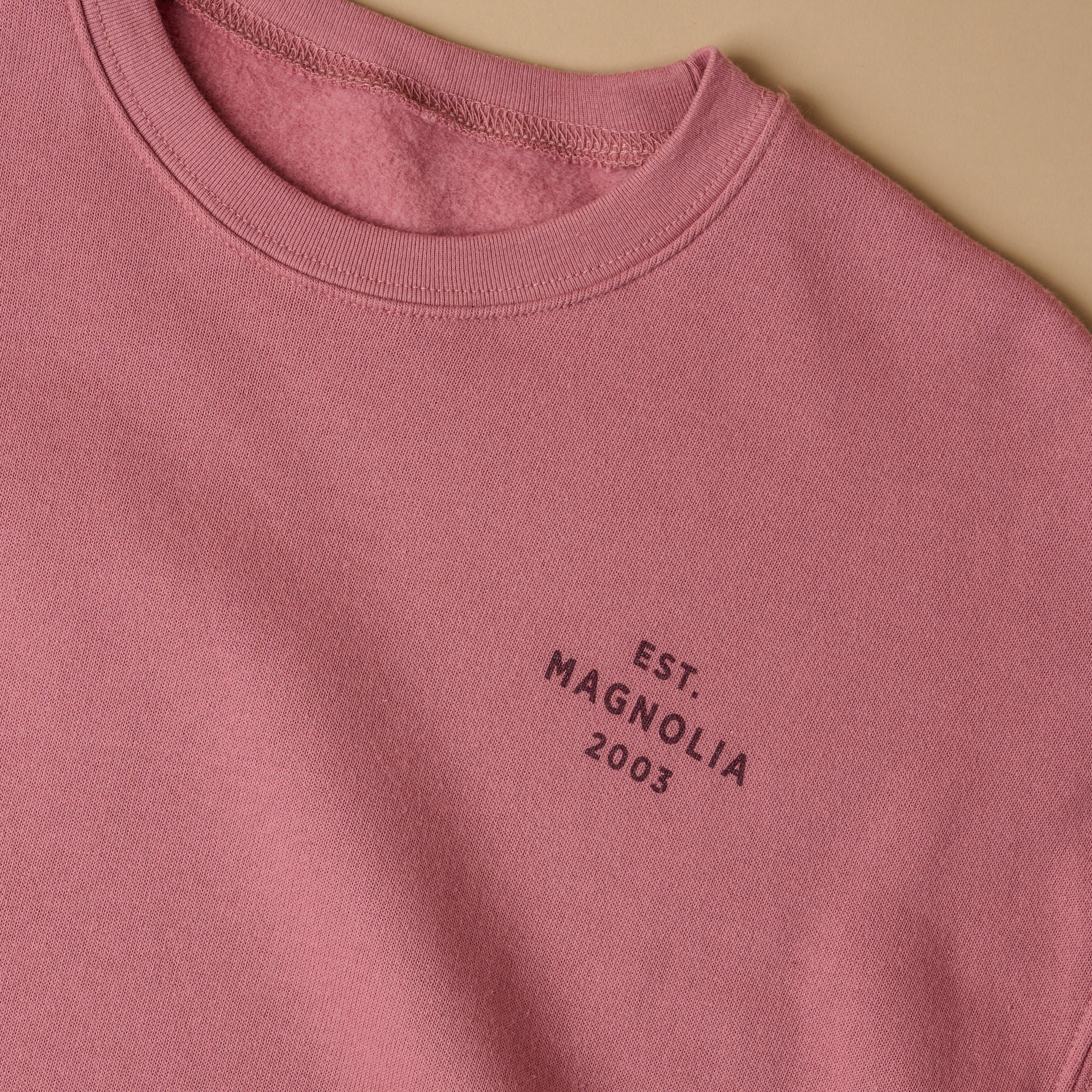 Close up of text on left chest. Reads EST. Magnoliass 2003 in plain font, all capital letters. 