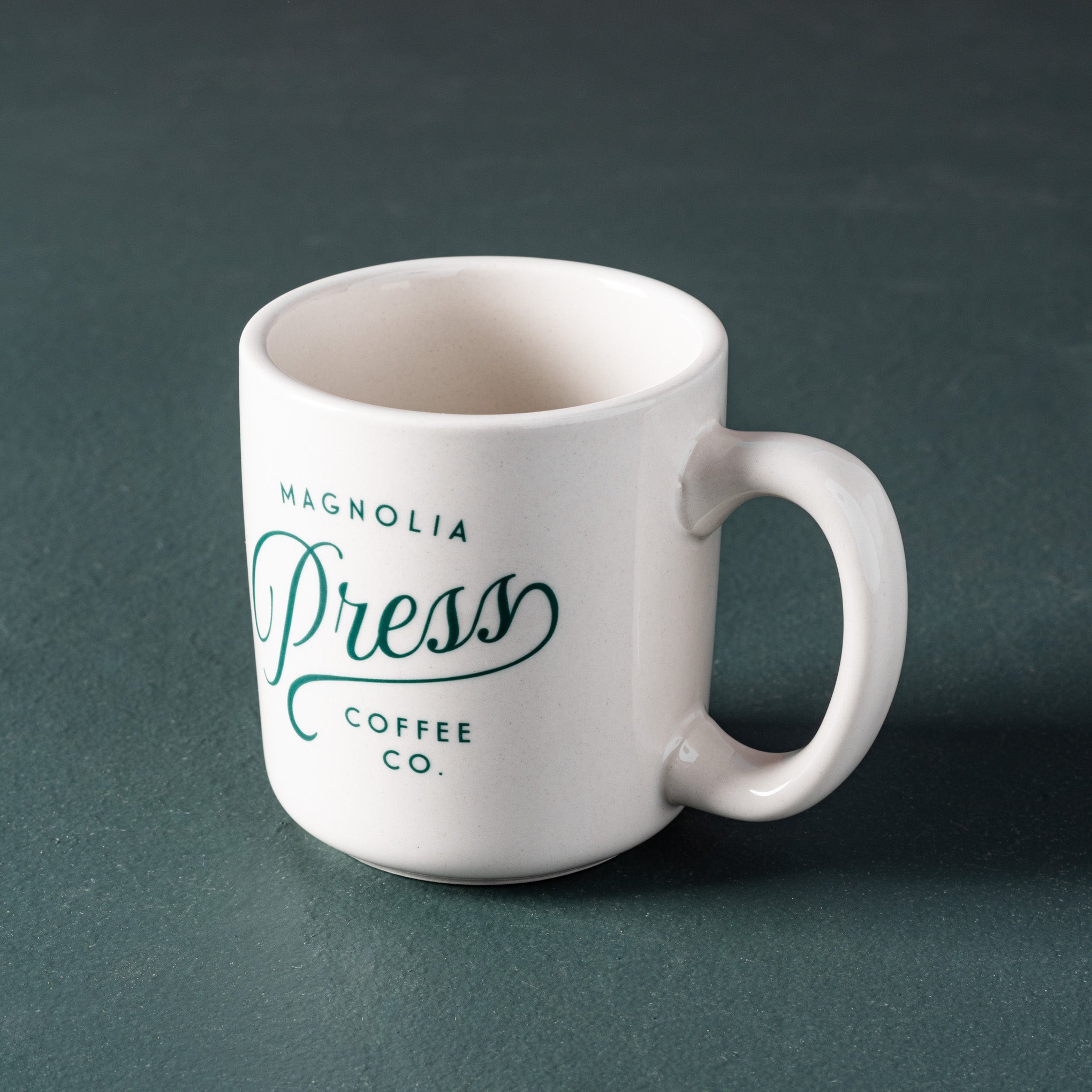 white ceramic coffee mug with Magnoliass Press script logo in emerald green