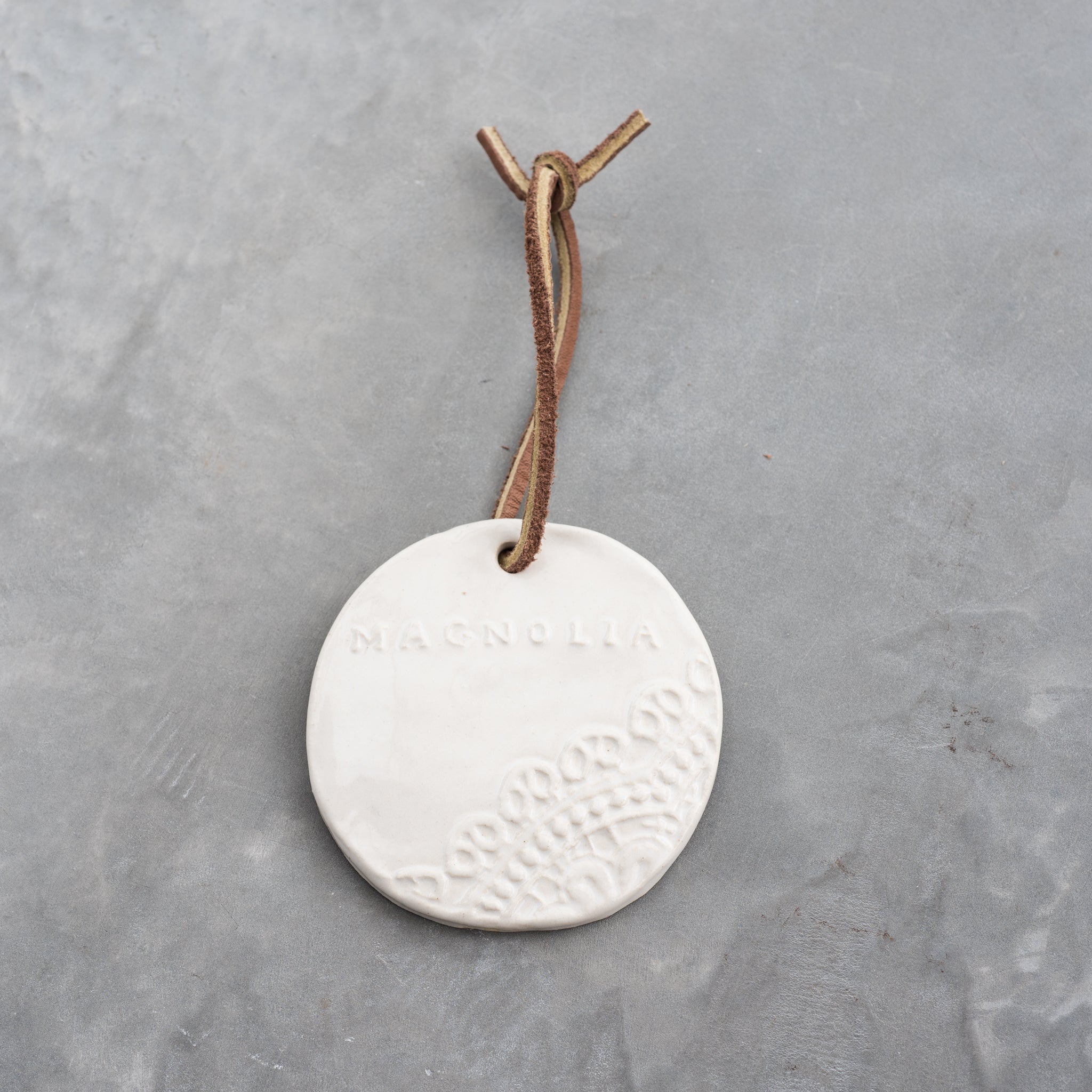ceramic circle ornament with lace detail and Magnoliass logo